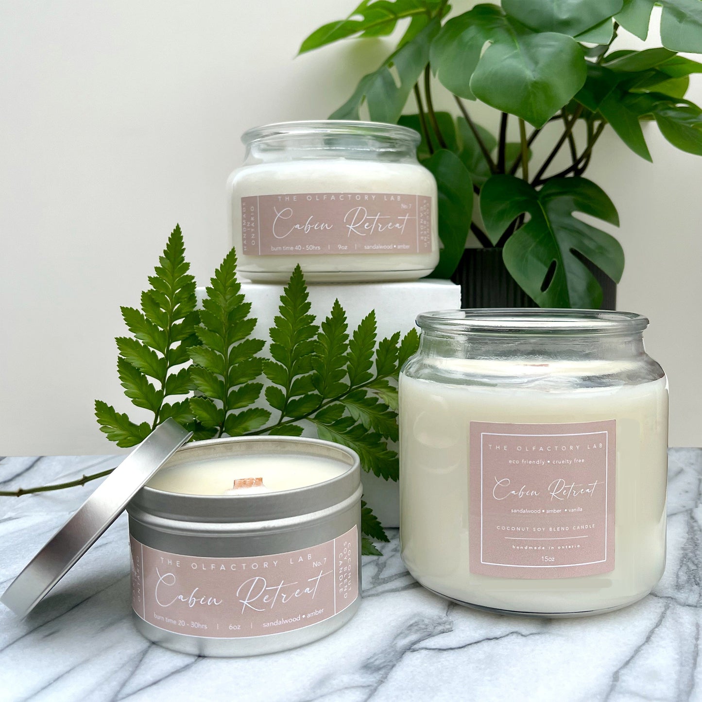 
                  
                    Cabin Retreat trio on marble counter with greenery in the background.
                  
                