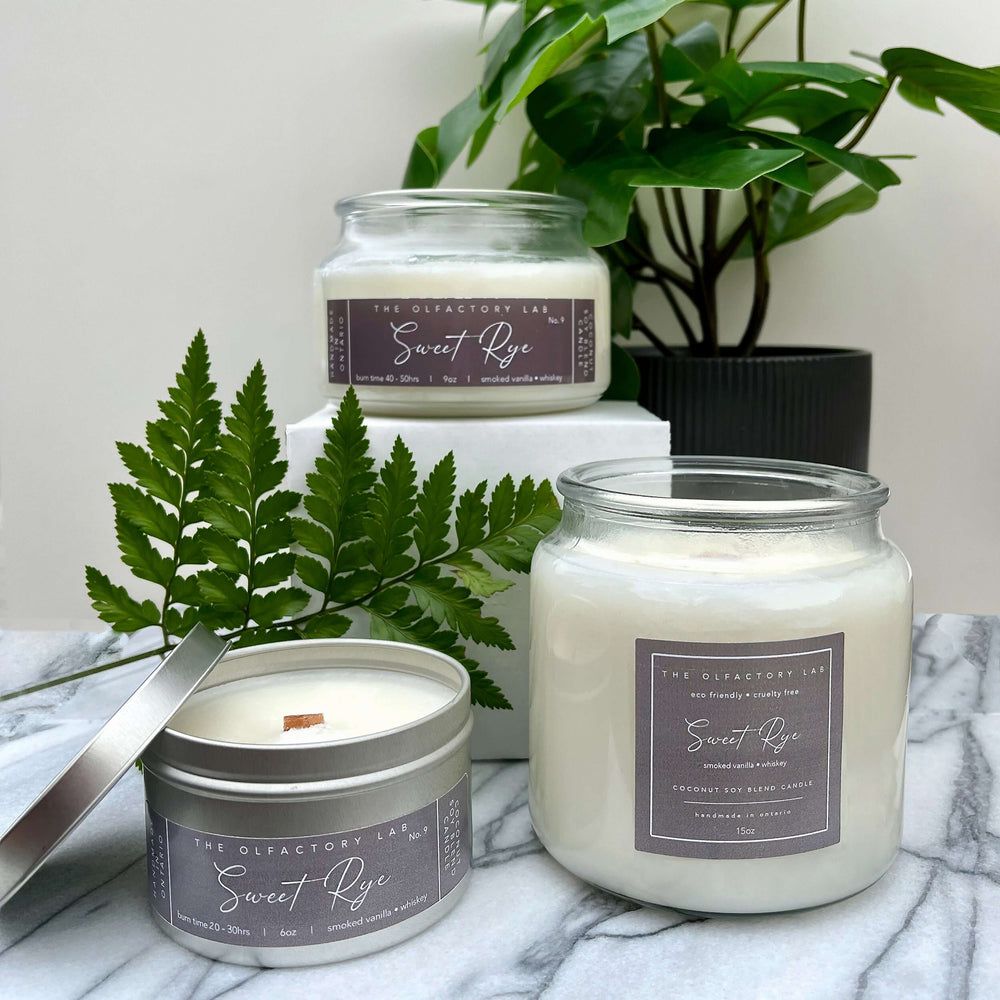 
                  
                    Trio of 15oz, 9oz, and 6oz Sweet Rye candles. Candles are displayed on a grey and white marble table with greenery in the background.
                  
                