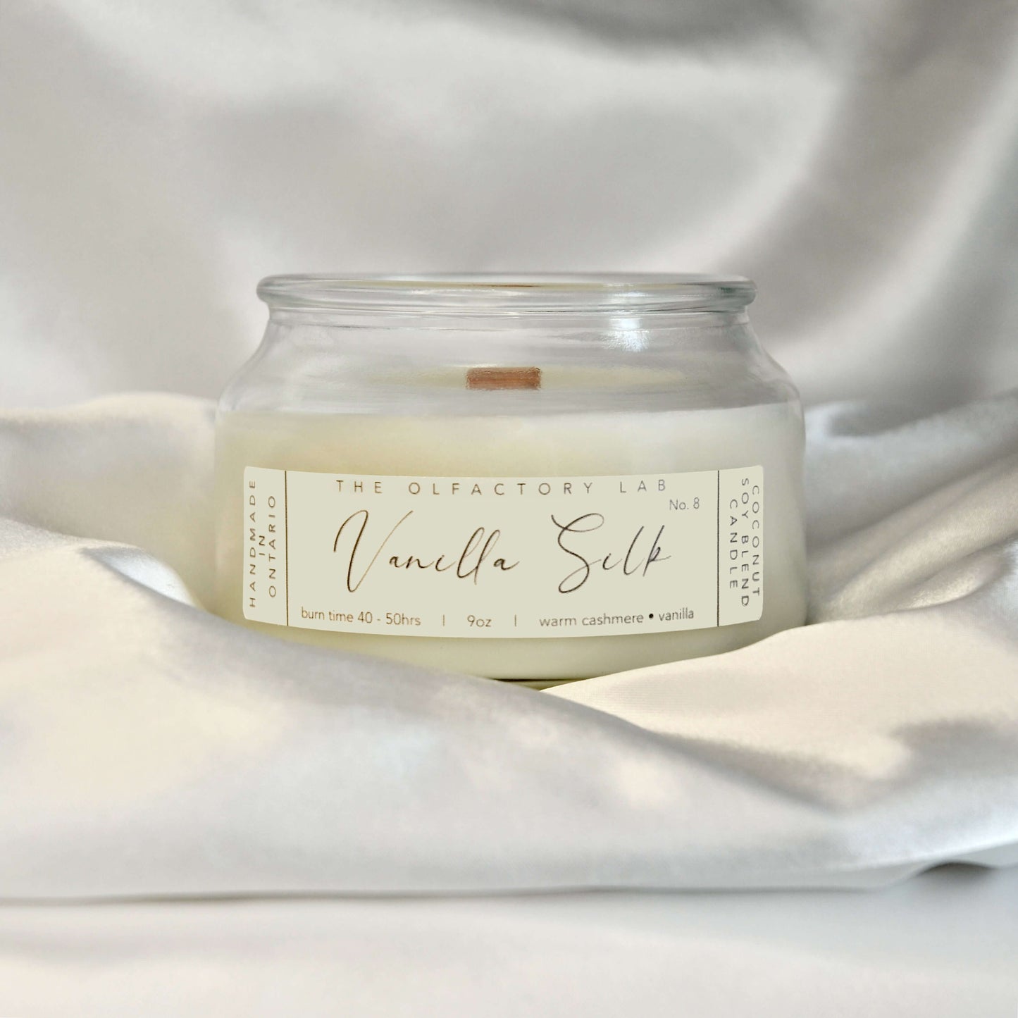 
                  
                    A 9oz white candle. Candle label is a rectangle shape in a soft yellow shade with grey cursive font reading Vanilla Silk. The candle is placed in the middle of a white satin pillow.
                  
                
